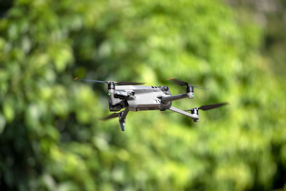 Inteligência Artificial — A sleek, modern drone hovering amidst a lush green backdrop, showcasing cutting-edge technology.